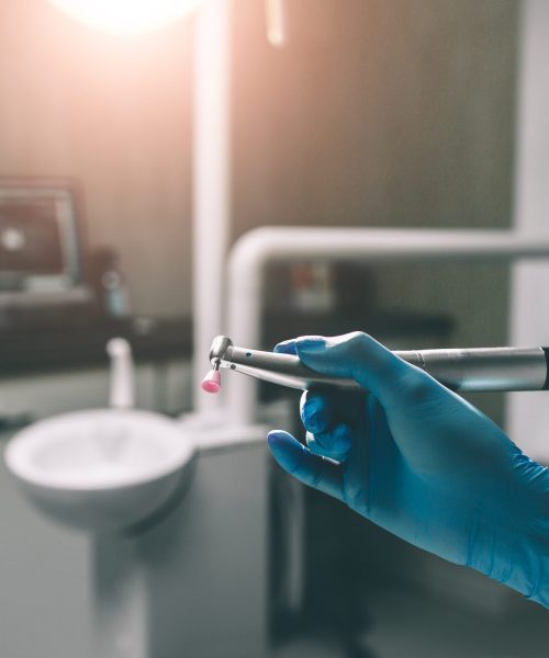 Detail of hand holding dental tools in dental clinic. Dentist Concept.